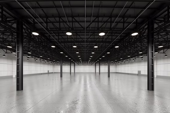 An empty warehouse interior with exposed steel roof framing and rows of pendant high-bay lights above a bare floor — warehouse insurance in Texas