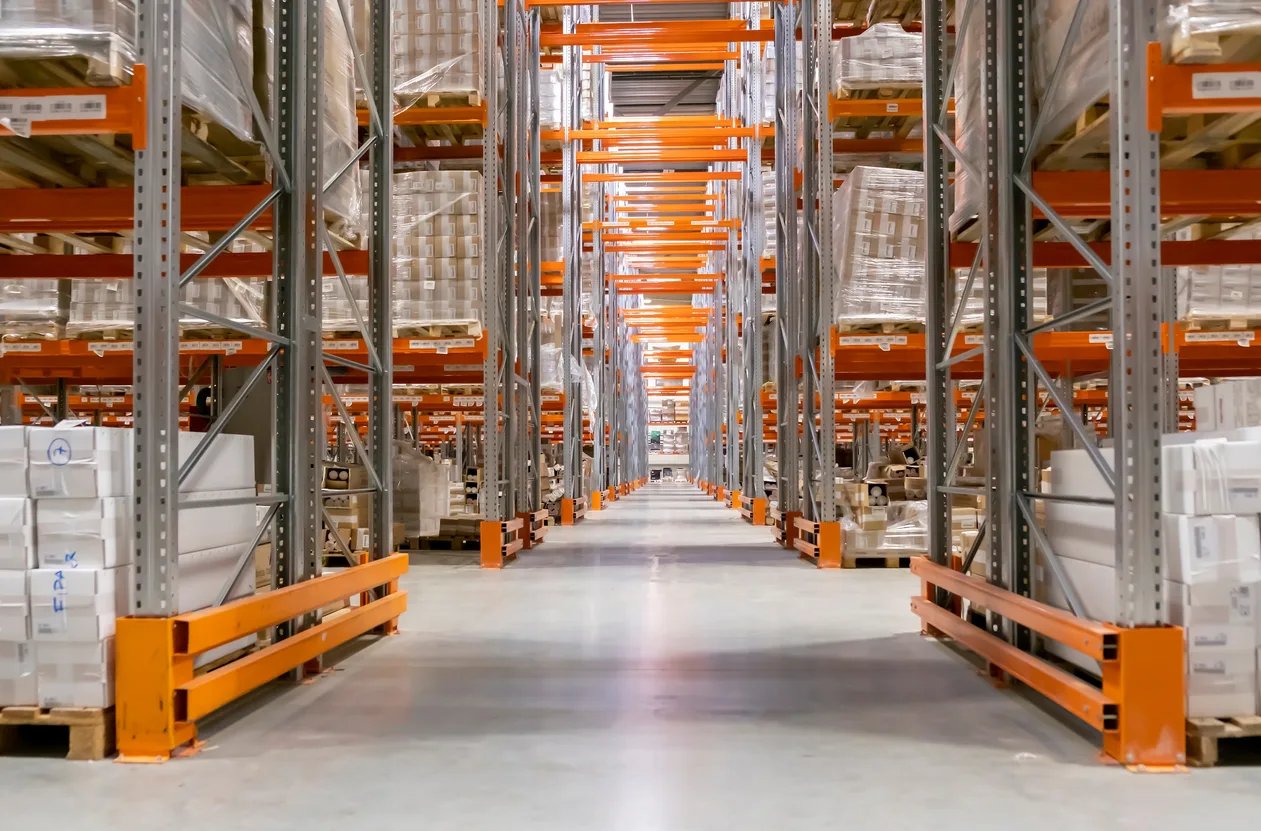 A long aisle between tall pallet racking stacked on both sides with shrink-wrapped pallets — warehouse insurance in Utah