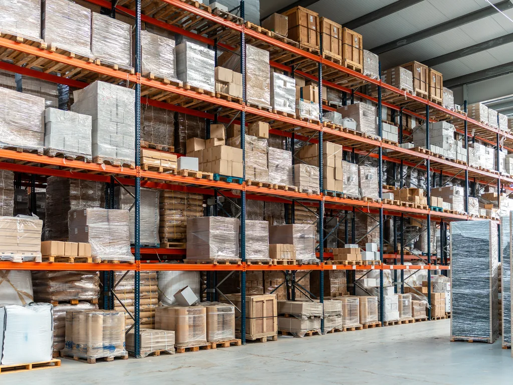 A run of pallet racking filled with wrapped pallets and cartons on several levels above floor-level stock — warehouse insurance in Vermont