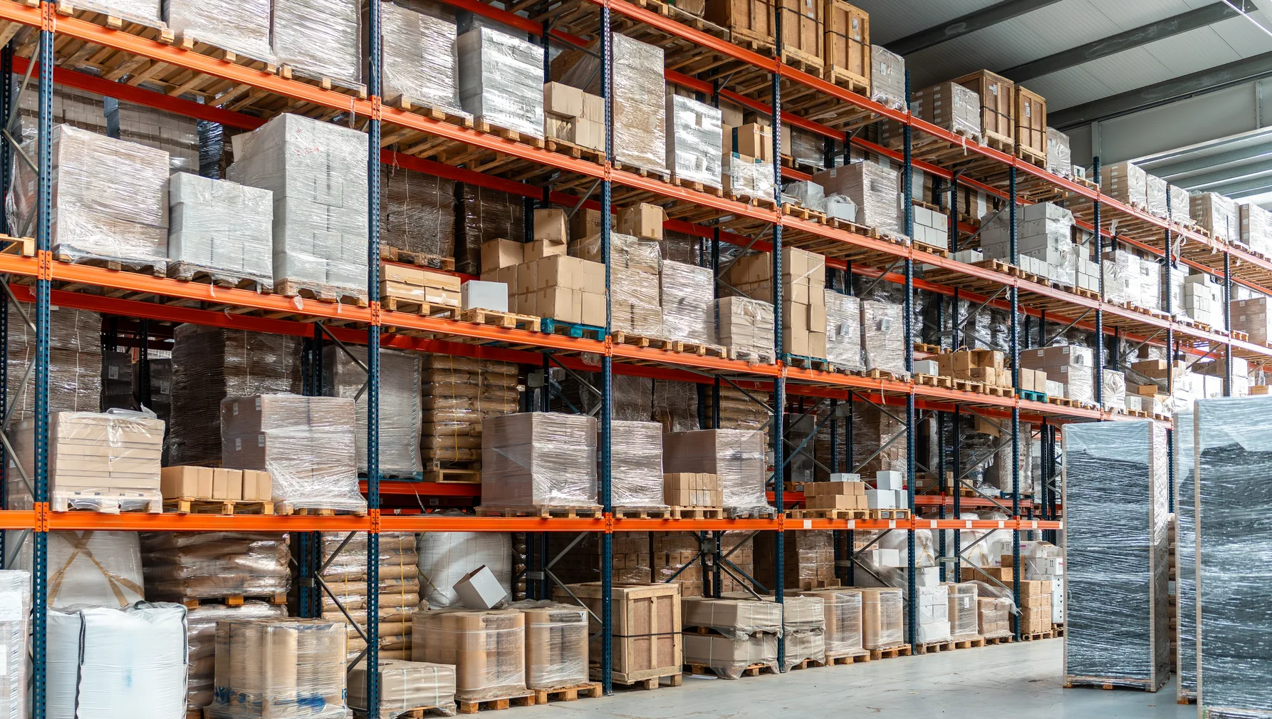A run of pallet racking filled with wrapped pallets and cartons on several levels above floor-level stock — warehouse insurance in Washington